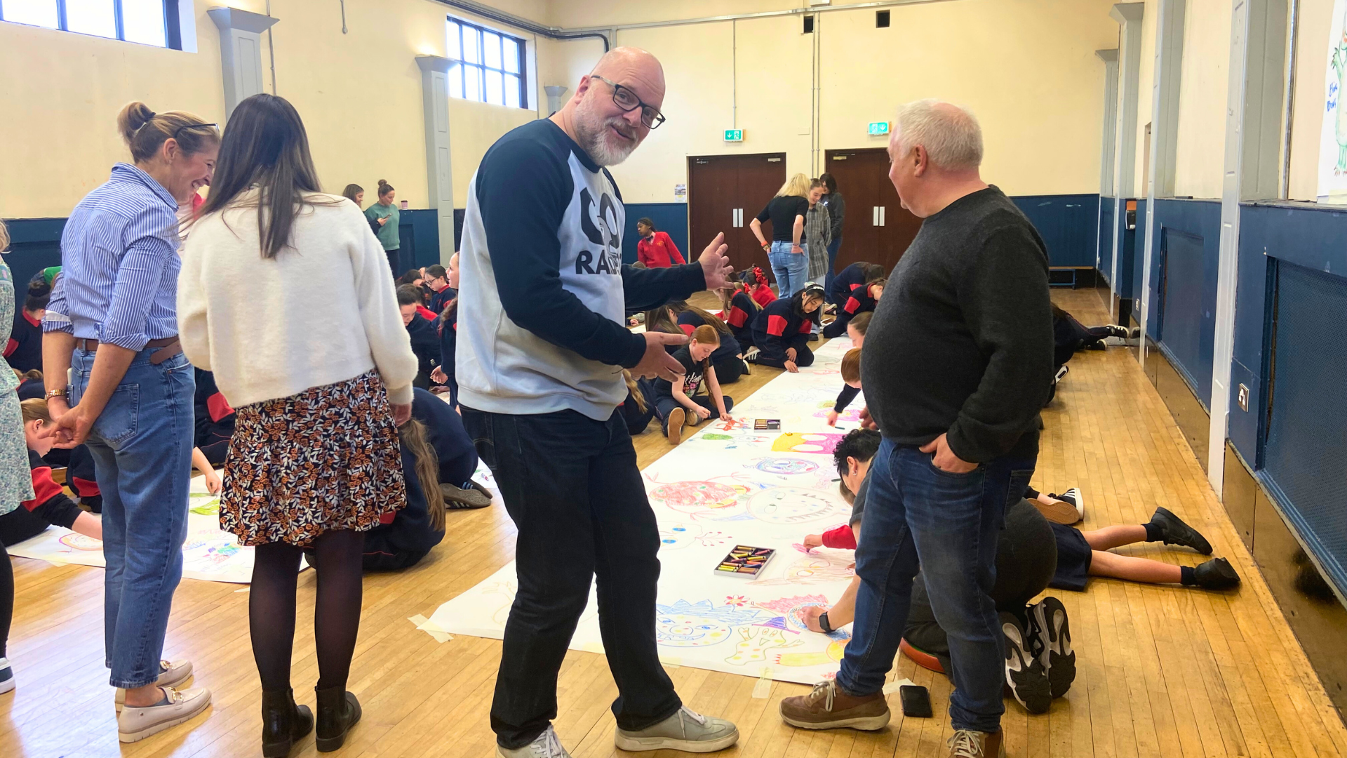 Children drawing a large monster doodle in their school gym 