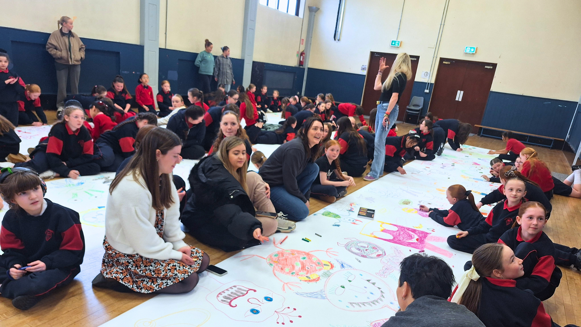 Children drawing a large monster doodle in their school gym