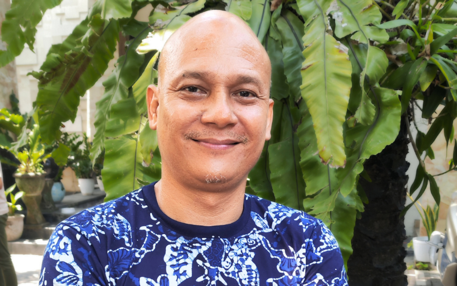 A photo of Faseh Hulisan standing outside, a tree in the background.