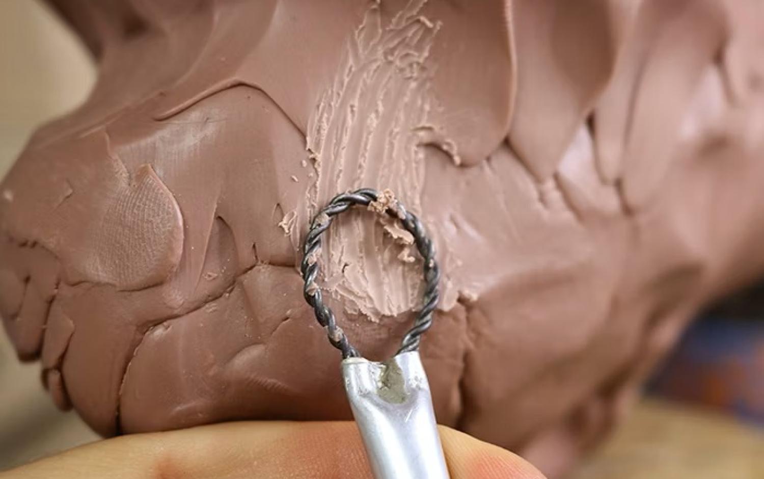 Twisted wire loop tool shaping and texturing clay sculpture.