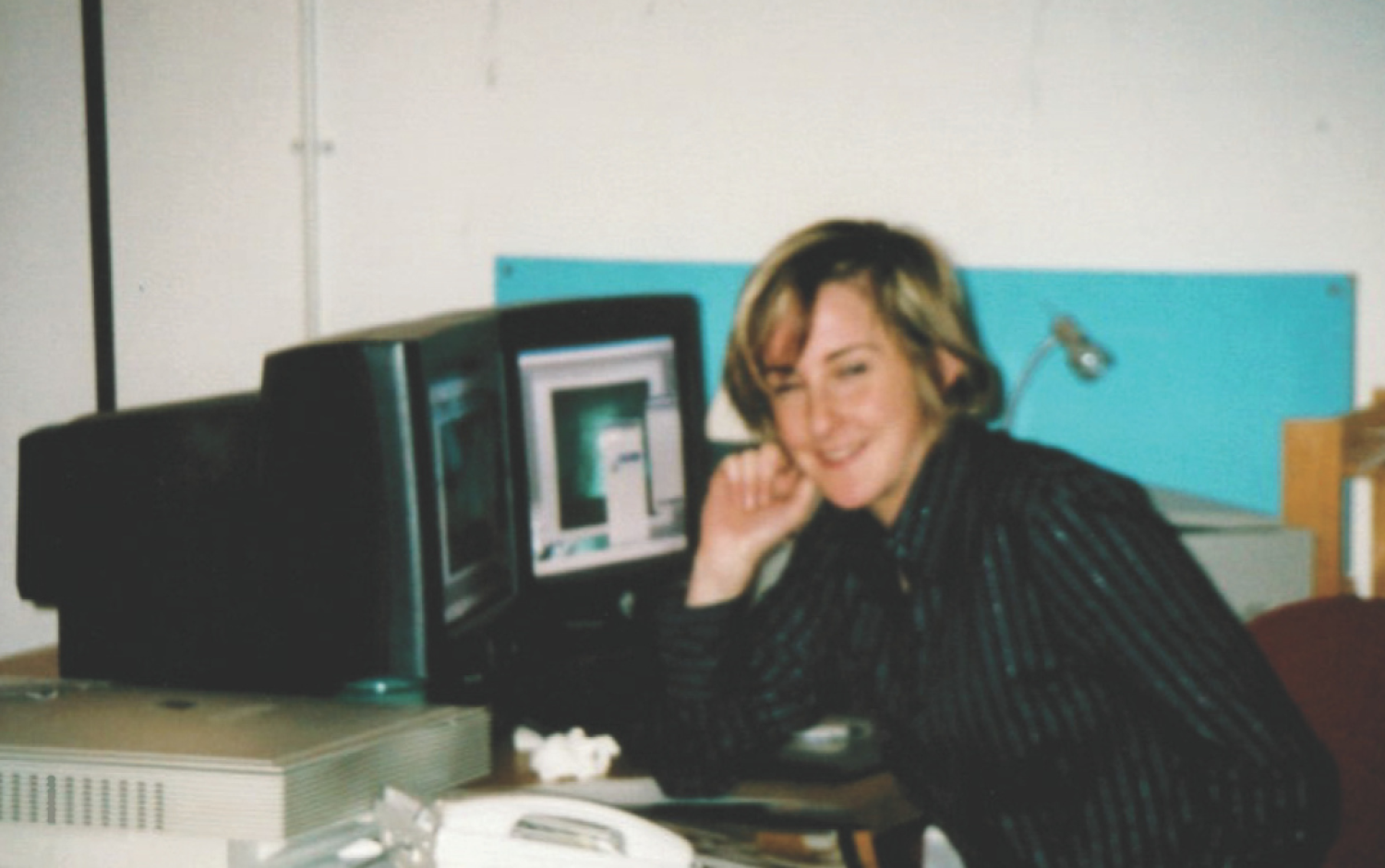 Person seated at a desk using a computer with a CRT monitor displaying a design or animation interface.