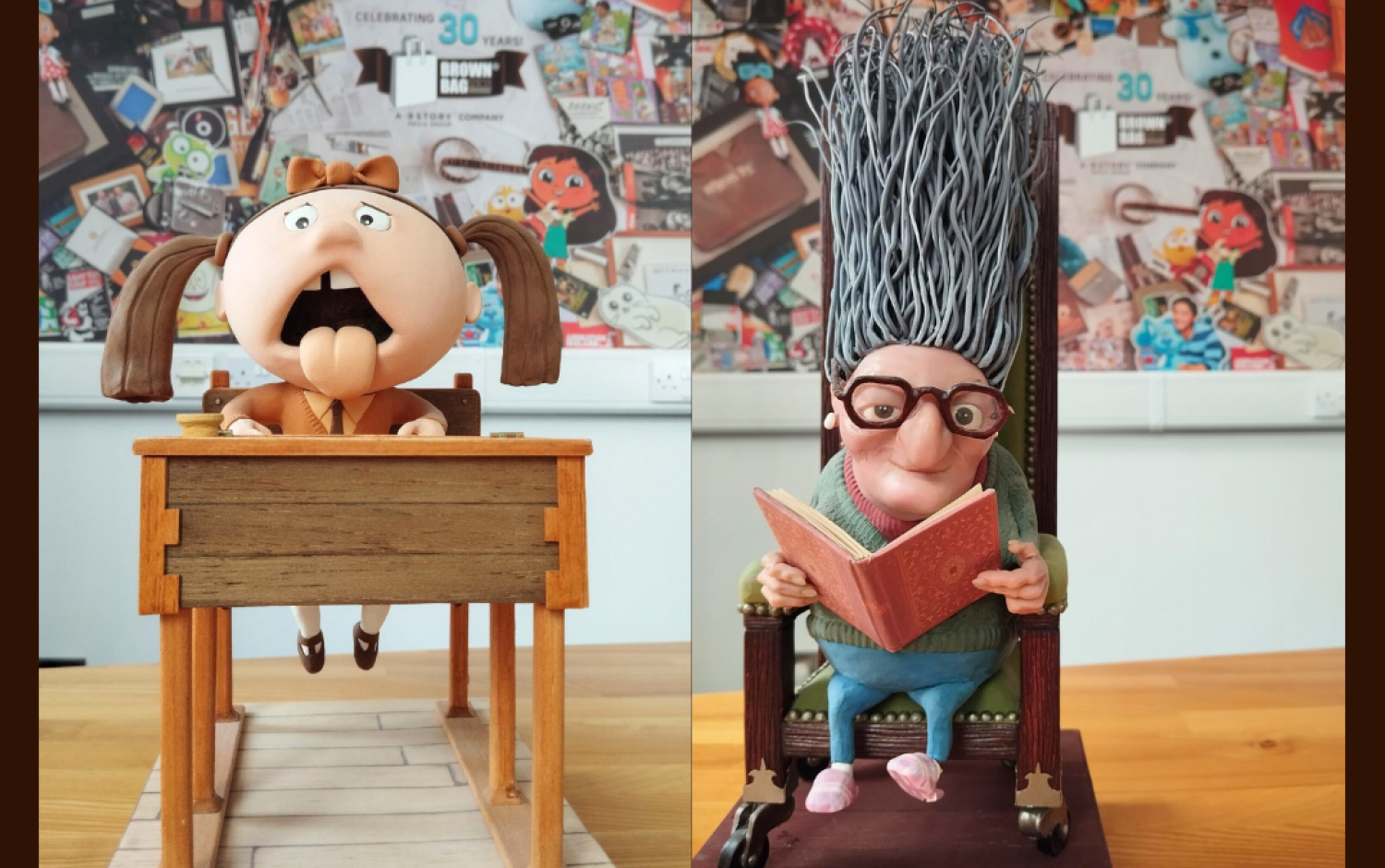 Two animation character models displayed on a table with a colorful backdrop of artwork.